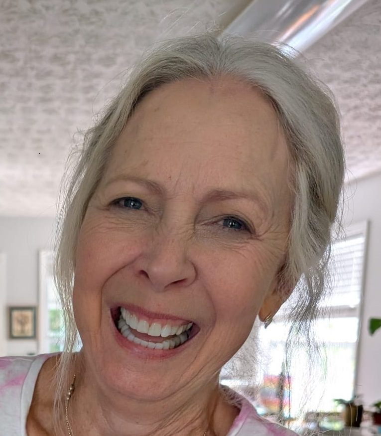 Smiling elderly woman with gray hair in a bright room.